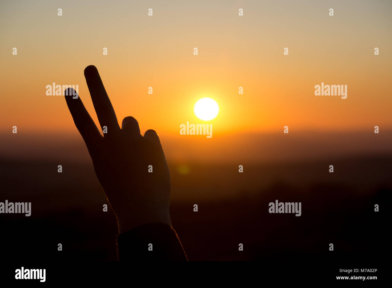 Ein friedenszeichen Geste wird von der untergehenden Sonne in Dartmoor, Großbritannien Silhouette Stockfoto