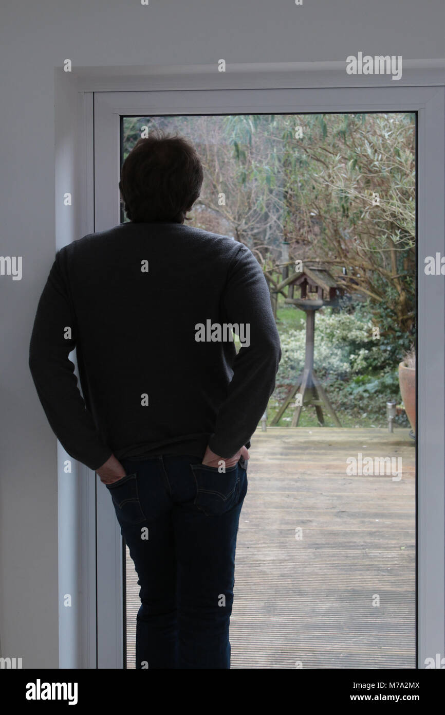 Mann in Türdurchgang in seinem Garten und Vogelbeobachtung Stockfoto