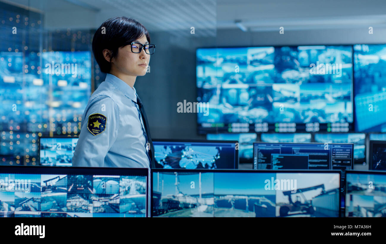 In den Kontrollraum Officer überwacht mehrere Bildschirme für verdächtige Aktivitäten. Er bewacht International bedeutende Logistikanlage. Stockfoto