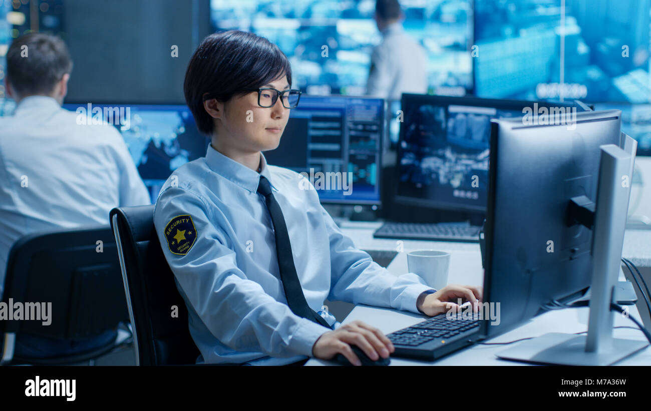 In der Security Command Center Officer, an seinem Arbeitsplatz überwacht mehrere Bildschirme für illegale Infiltration. Sie bewachen wichtige Person. Stockfoto
