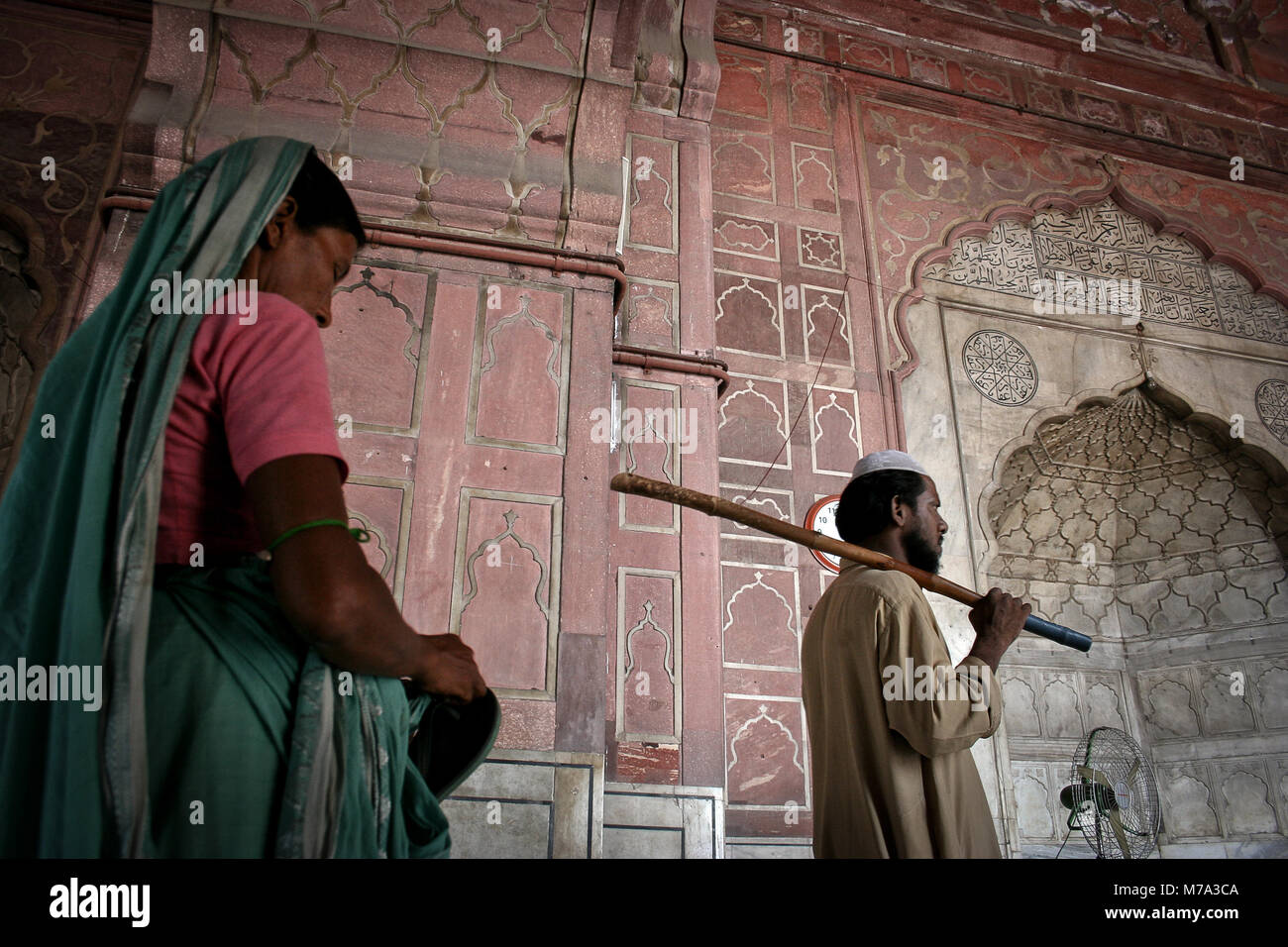 Old Delhi, Indien: Der Wächter der Jama Masjid Moschee begleitet eine Frau im Inneren. Stockfoto