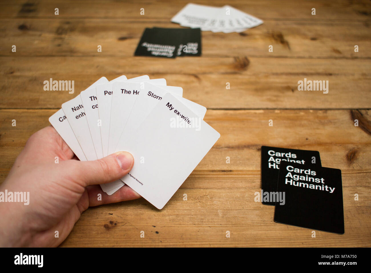 Karten gegen die Menschlichkeit, ein Party Spiel für grausamen Menschen, dargestellt auf einem Holztisch Stockfoto