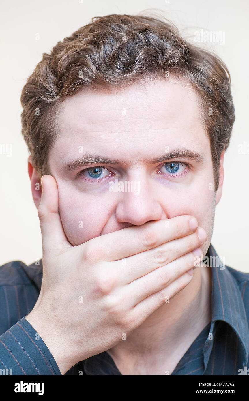 Ruhige, Stille halten. Porträt der jungen blauäugigen Mann seinen Mund geschlossen halten mit den Fingern auf weißem Hintergrund. Stockfoto