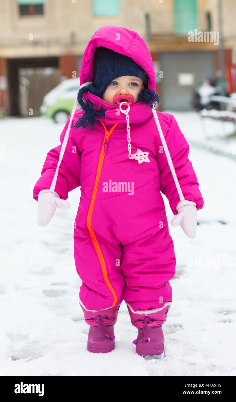 Adorable Kleinkind Baby Mädchen in einem magenta Schnee Anzug spielen auf  dem Schnee Stockfotografie - Alamy