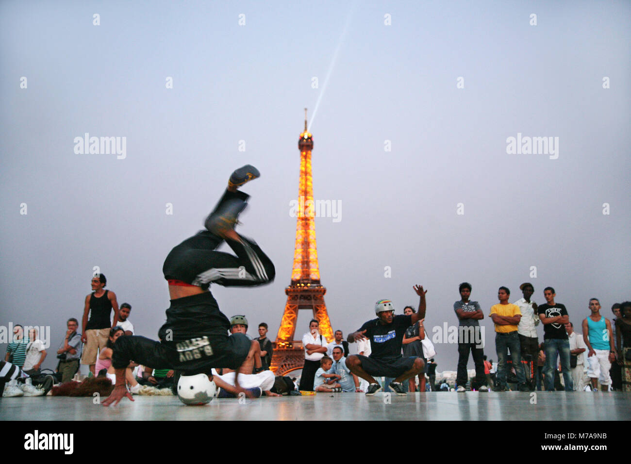 Breakdancer, eine Menge von Touristen in der Nähe von Eiffelturm unterhalten wie abends mit den Städten Lichter einschalten, 1. Juli 2009, Paris, Frankreich. Stockfoto