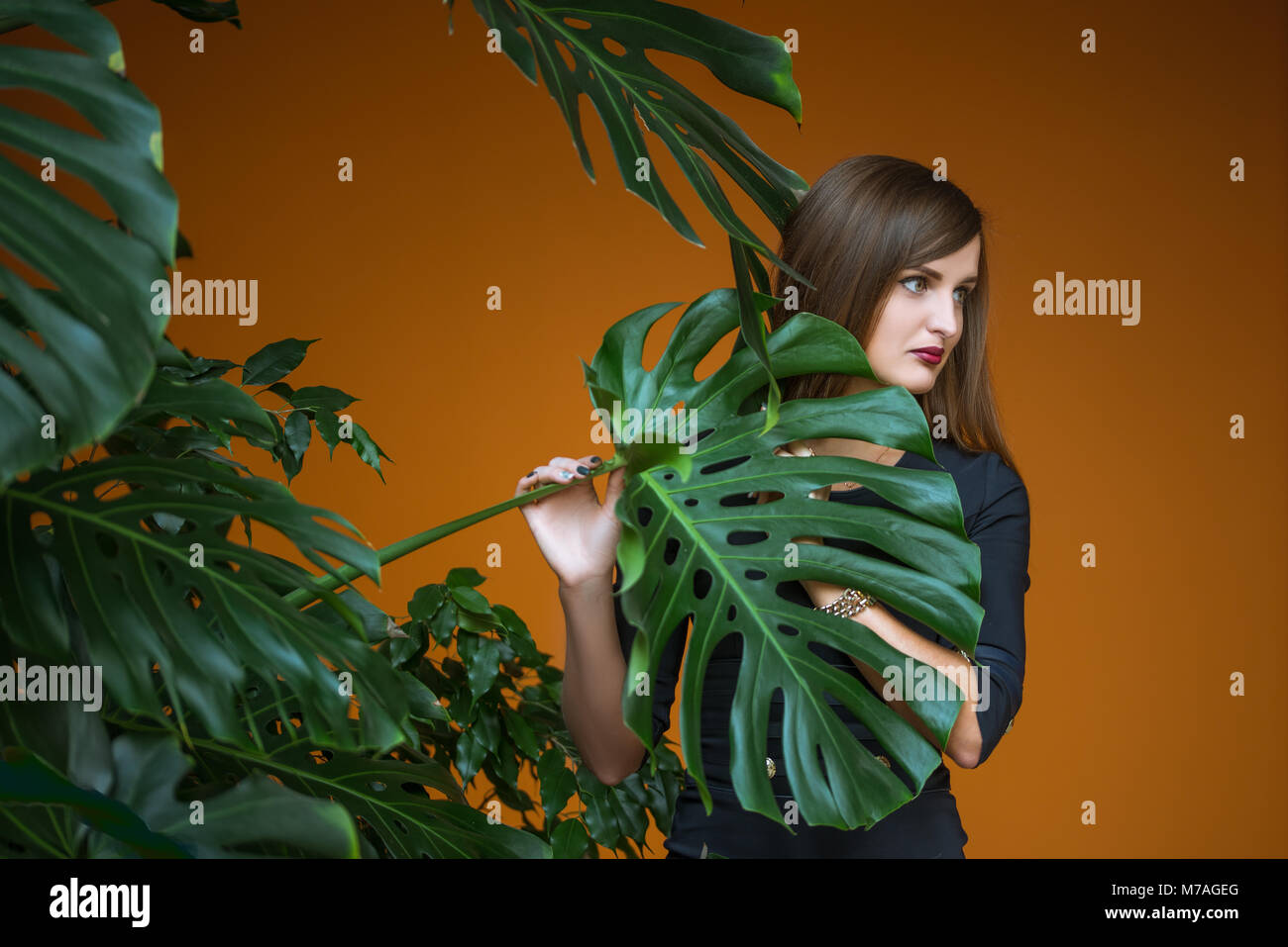 Pretty girl Holding von Hand Stiel von Palm auf braunem Hintergrund Stockfoto