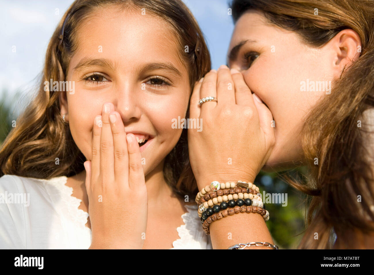 Nahaufnahme einer Mitte der erwachsenen Frau ihre Tochter ins Ohr flüstern Stockfoto