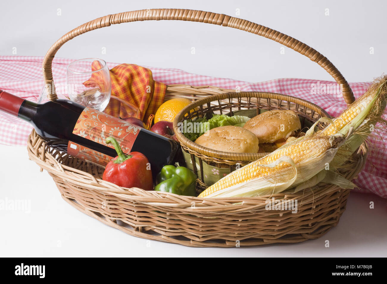 Nahaufnahme der Burger mit einer Flasche Wein und Obst in einem Picknickkorb Stockfoto