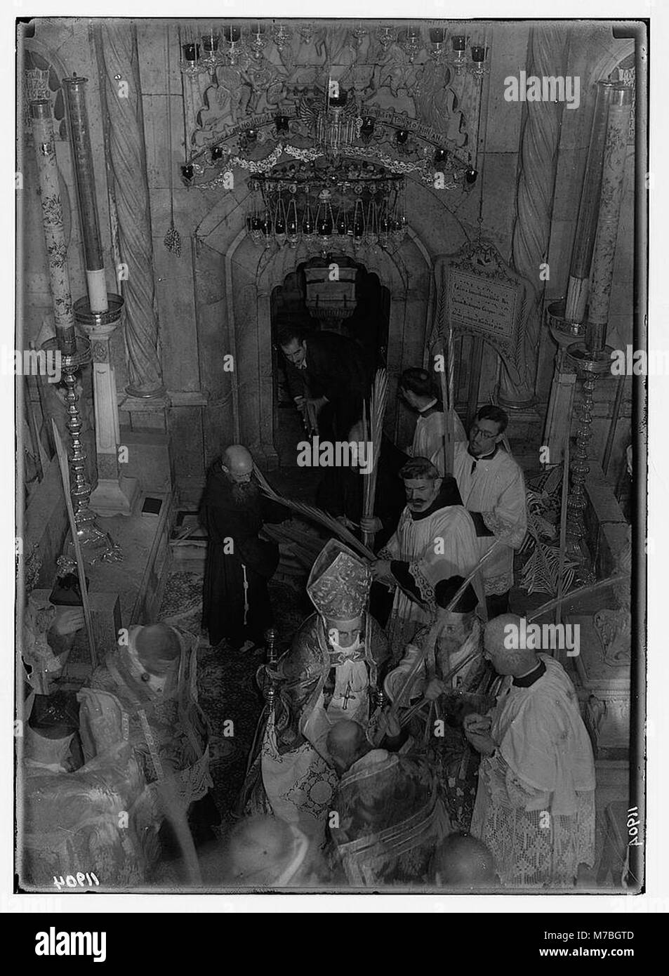 Dieses Foto aus dem Jahr 1941 zeigt die Palmensonntagsprozession in Jerusalem und zeigt den Segen der Palmen und ihre zeremonielle Bewegung aus dem Grab in der Grabeskirche. Es beleuchtet die religiösen Praktiken und die Bedeutung der Osterzeremonien in der Stadt. Stockfoto