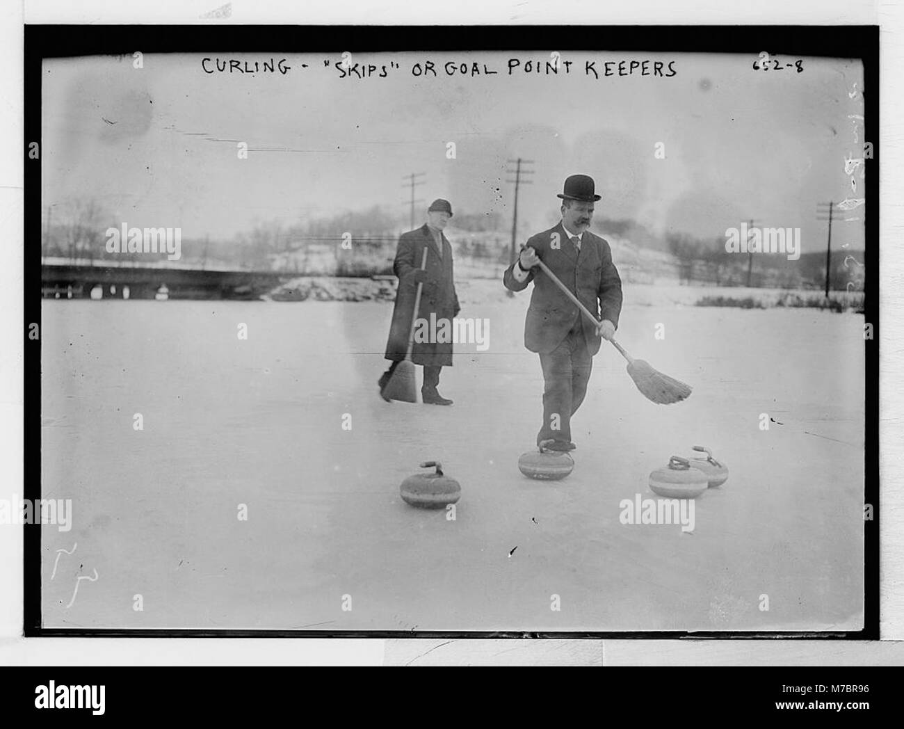 Dieses Bild zeigt Lockenwickler auf dem Spielfeld während eines Spiels, mit einem Fokus auf den Skips oder Torpunkthütern, die für die Führung der Strategie des Teams und die Führung der Platzierung der Steine verantwortlich sind. Stockfoto