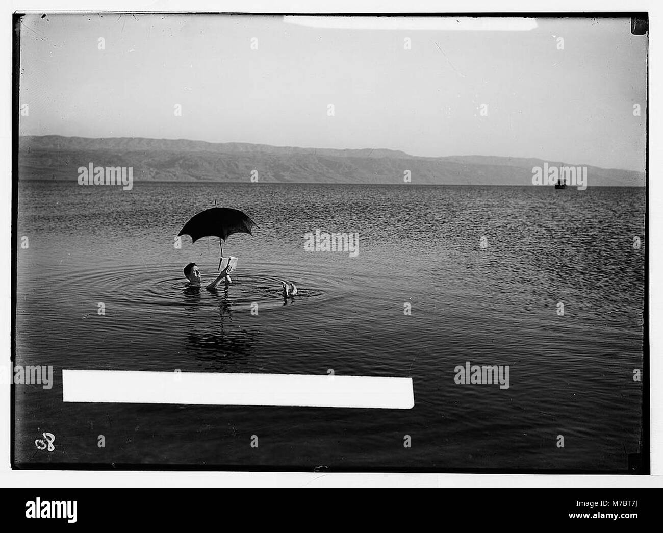 Toten Meer. Mann mit Buch und Sonnenschirm floating auf Bouyancy (d. h., Auftrieb) LOC matpc zeigen.05917 Stockfoto