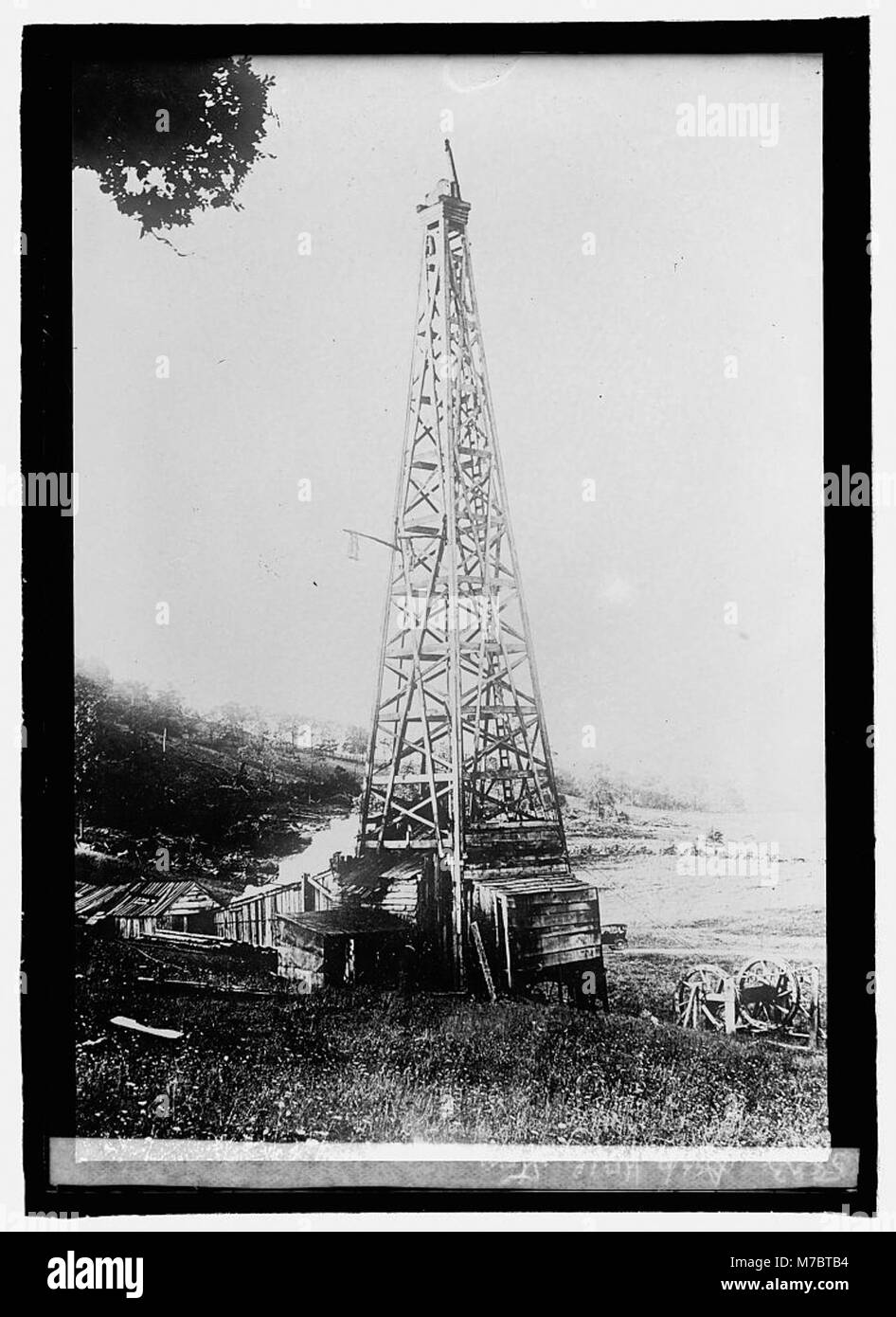 Ein historisches Foto, das die Geschichte eines tiefen Brunnens feststellt, wahrscheinlich in Verbindung mit früherer industrieller oder landwirtschaftlicher Nutzung. Das Bild zeigt die technologischen und technischen Fortschritte dieser Zeit. Stockfoto