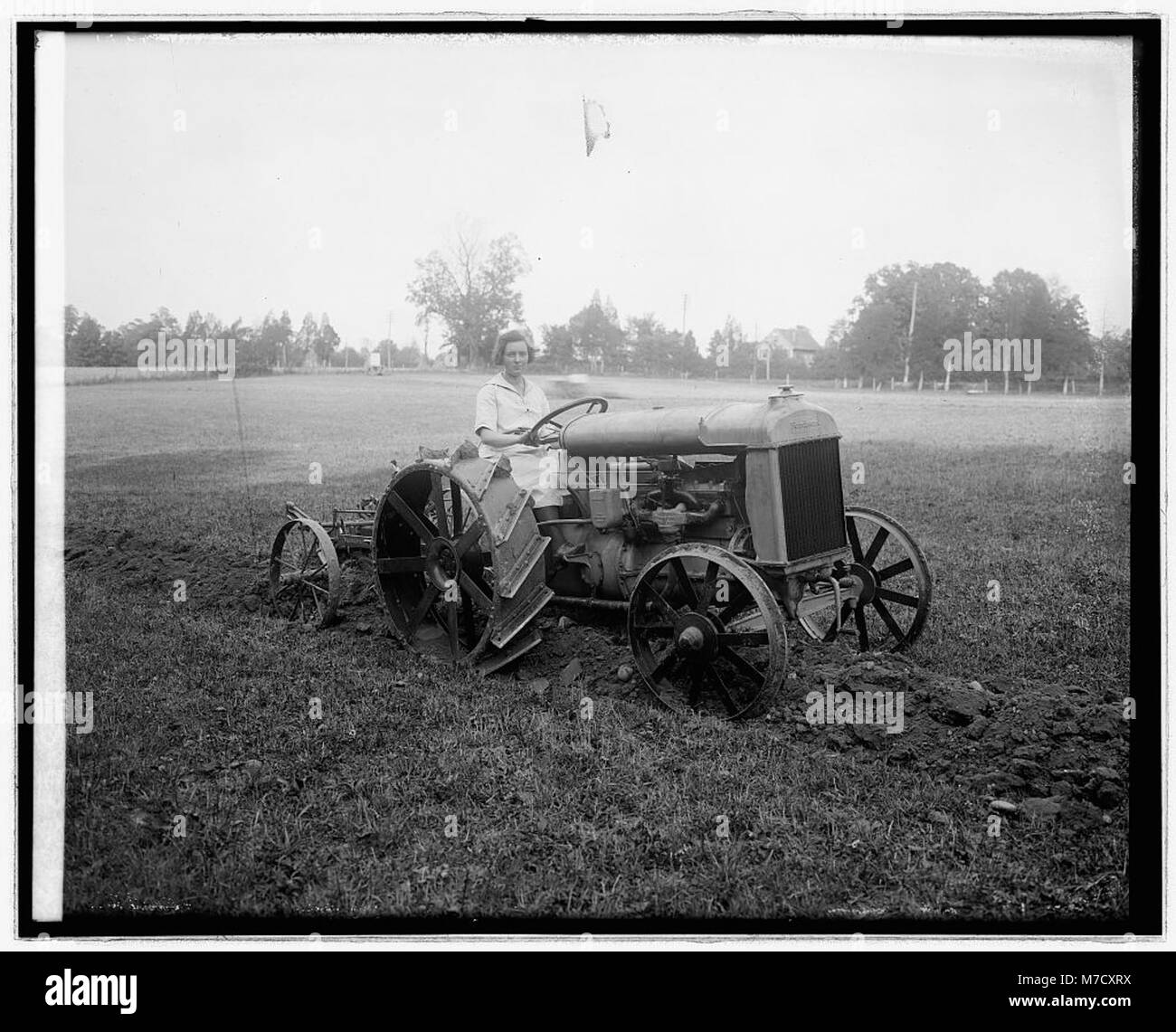 Eine Demonstration eines Ford-Traktors, der seine Fähigkeiten bei landwirtschaftlichen Aufgaben demonstriert. Das Bild zeigt die Rolle der Ford-Traktoren bei der Modernisierung der landwirtschaftlichen Techniken im 20. Jahrhundert. Stockfoto