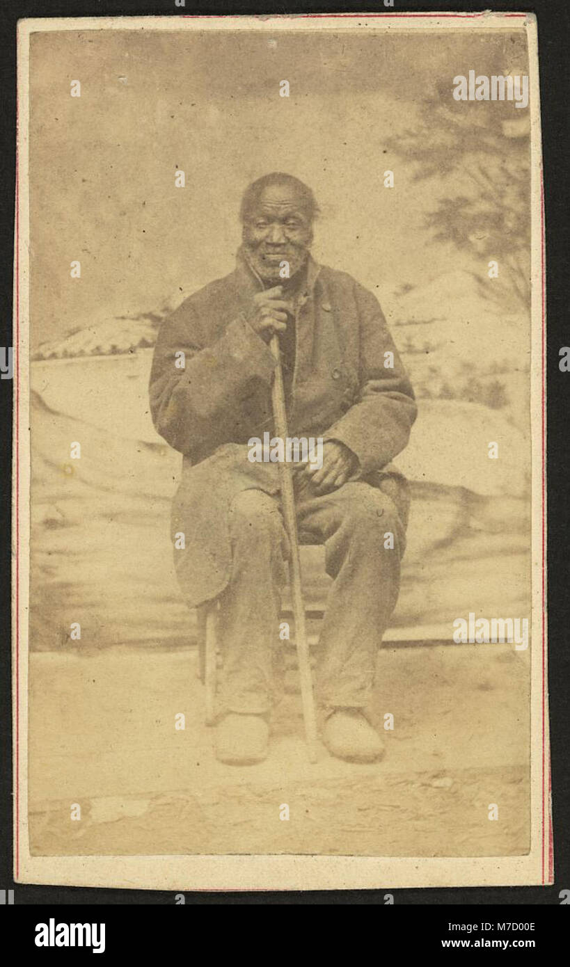 Ein abendfüllendes Porträt eines älteren Afroamerikaners mit einem Stock, der seine würdevolle Haltung zeigt und einen Einblick in sein Leben während des frühen 20. Jahrhunderts bietet. Stockfoto