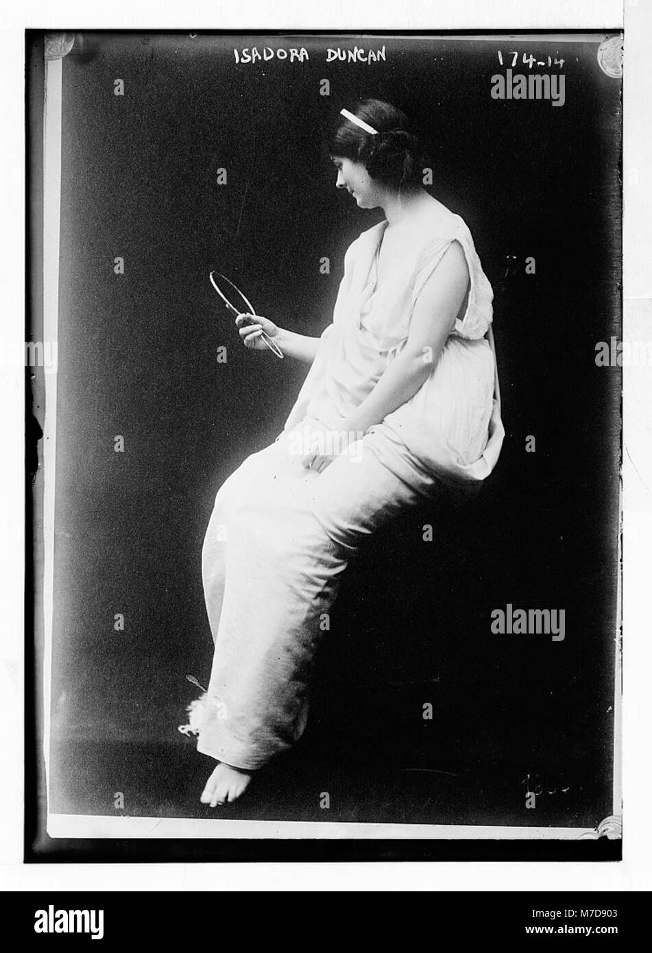 Isadora, dargestellt in einer Toga mit einem aussehenden Glas, fängt den klassischen Stil und die Eleganz der antiken römischen Kleidung ein und präsentiert einen historischen Modemoment. Stockfoto