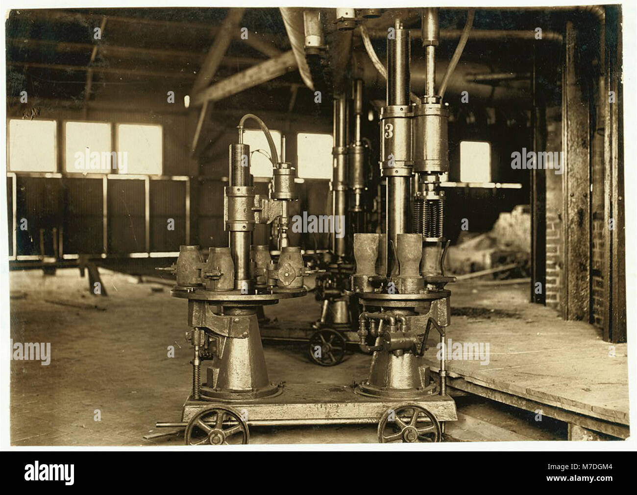 Diese Abbildung zeigt eine Maschine, die zum Durchblasen von vier Milchflaschen auf einmal entwickelt wurde und die technologischen Fortschritte in der Flaschenherstellung bei Travis Glass Co., Clarksburg, West Virginia, widerspiegelt. Stockfoto