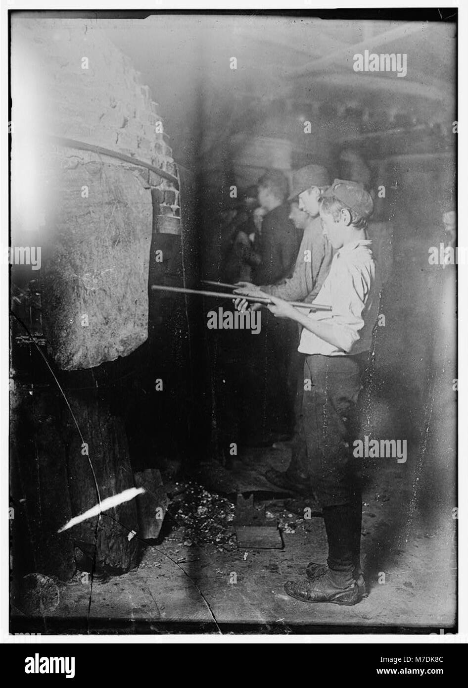 Jungen, die in einer Glasfabrik in Grafton, West Virginia, arbeiten im „Glory-Hole“-Ofen, erwärmen Glasobjekte für die Fertigstellung. Stockfoto