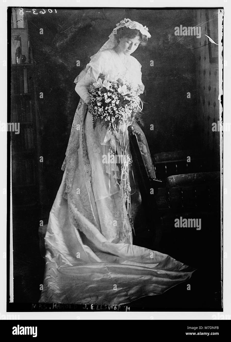 Ein Foto von Mrs. Harold J. Ellsworth mit einem Blumenstrauß. Das Bild fängt einen Moment der persönlichen Feier oder Anerkennung ein und hebt ihre Kleidung und die elegante Umgebung hervor. Stockfoto