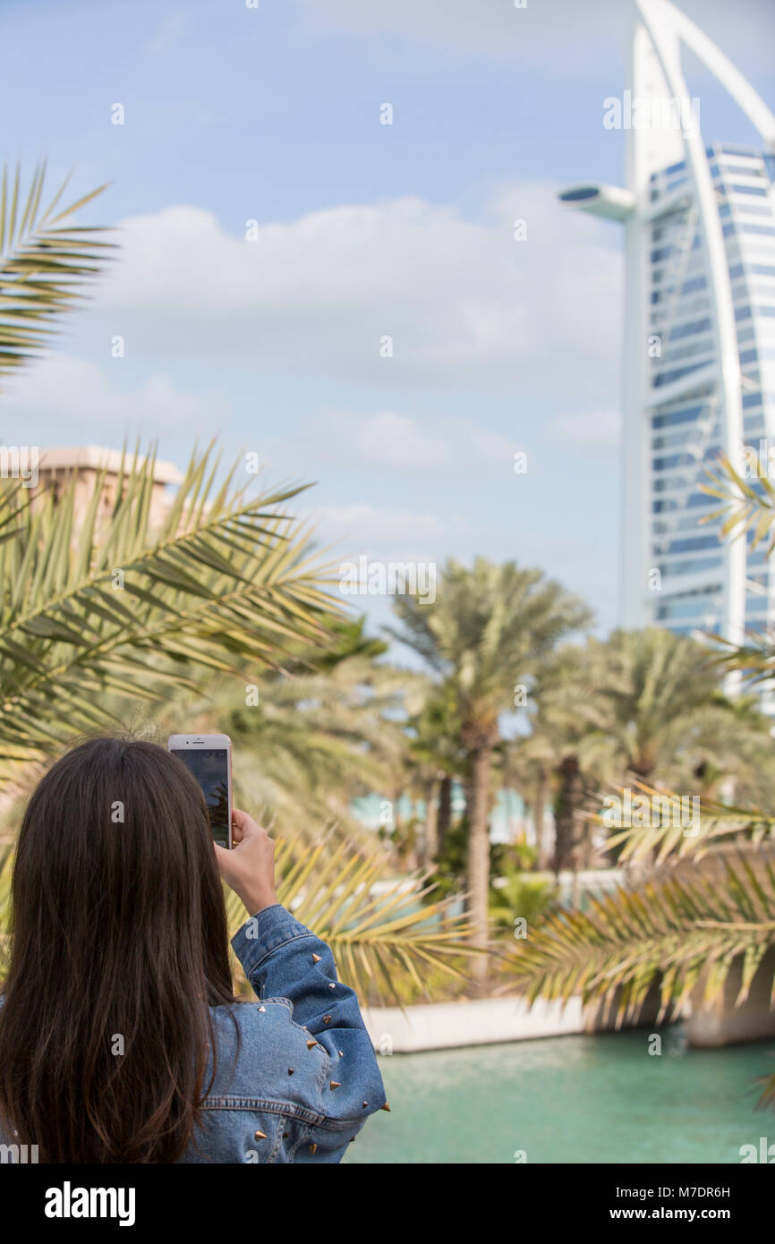 Rückansicht eines weiblichen Touristen, die Bilder von Hotel Burj Al Arab, Madinat Jumeriah mit einem Mobiltelefon Stockfoto