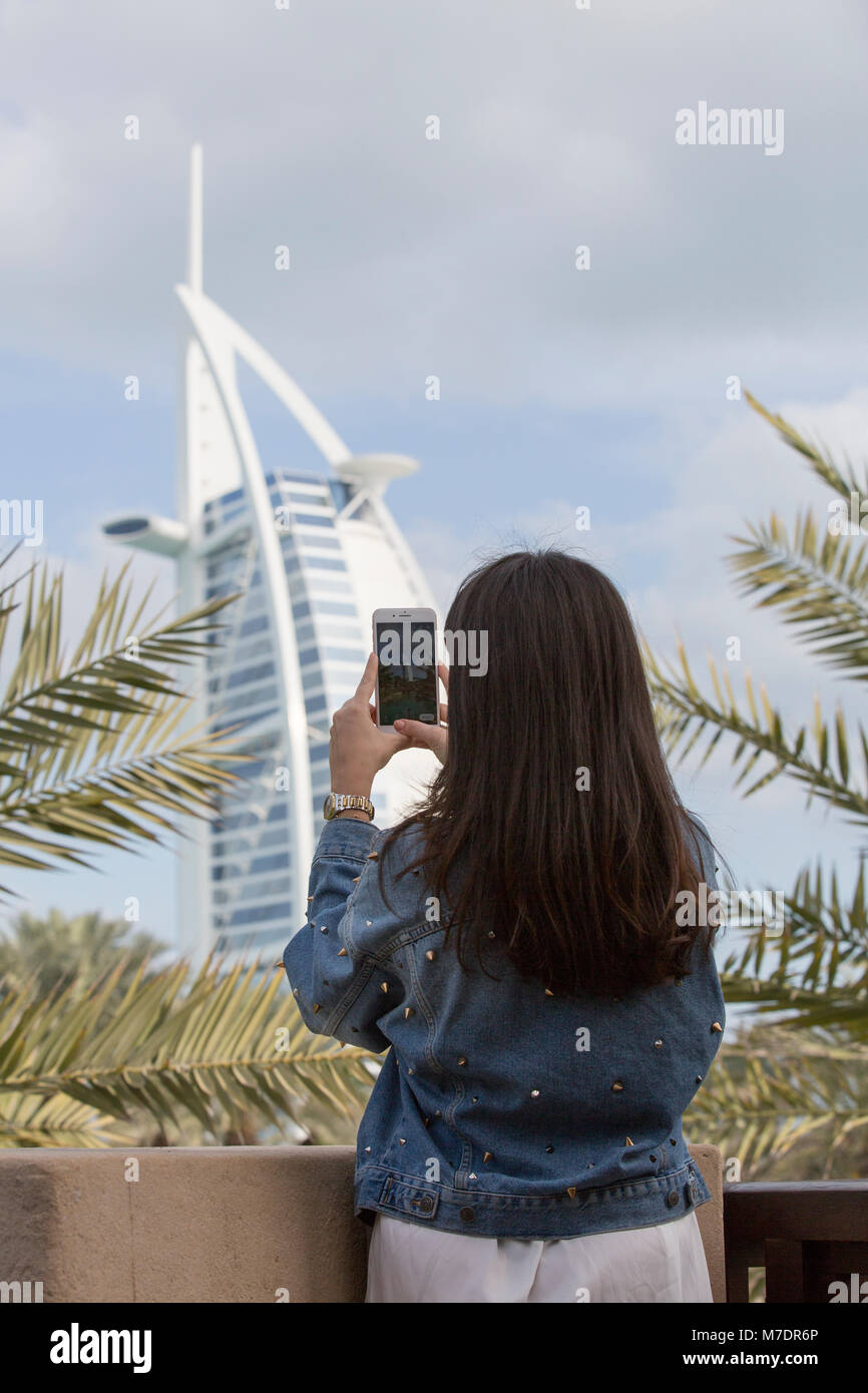 Rückansicht eines weiblichen Touristen, die Bilder von Hotel Burj Al Arab, Madinat Jumeriah mit einem Mobiltelefon Stockfoto