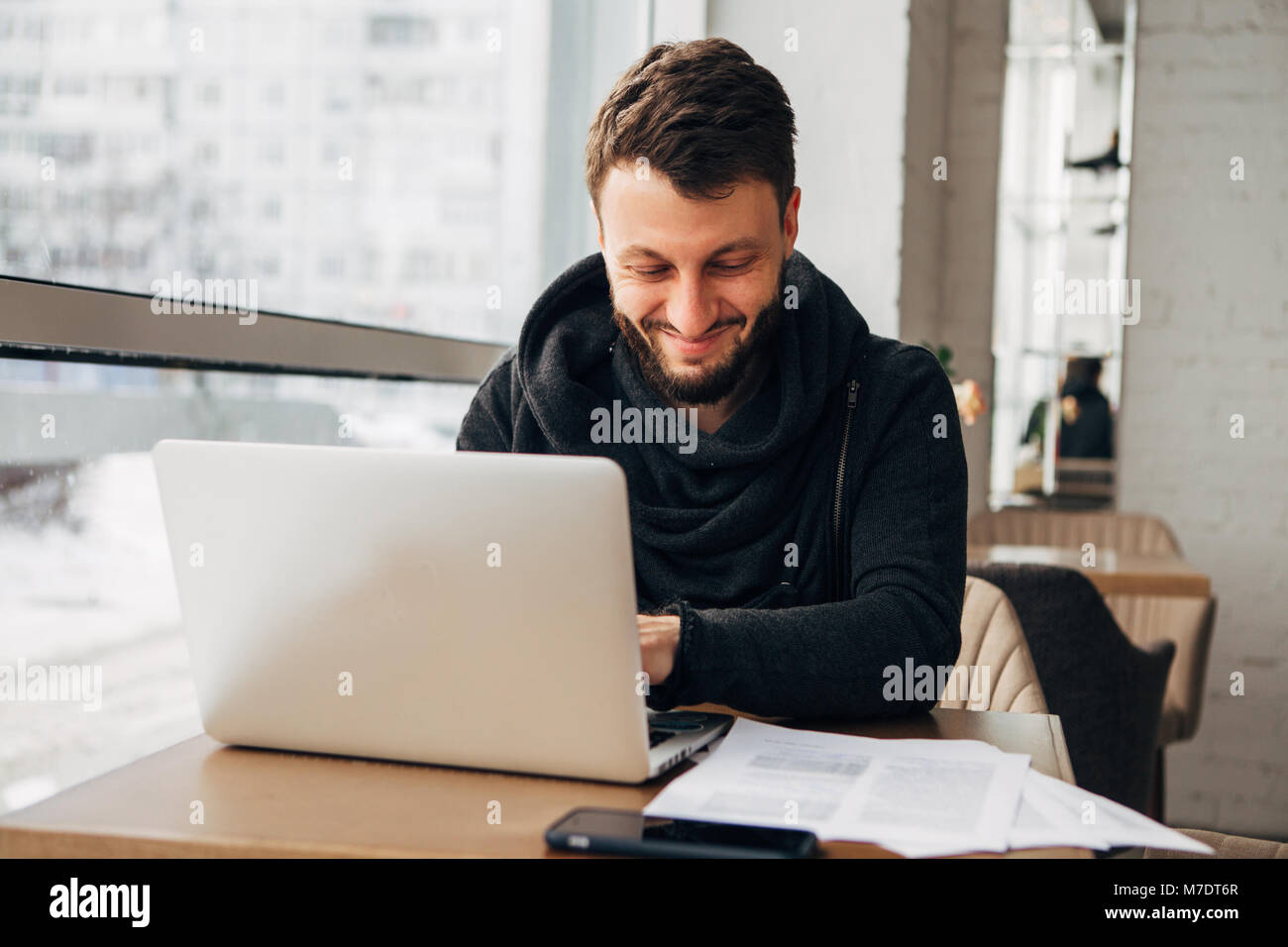 Ein junger Geschäftsmann arbeitet in einem Cafe mit einem Laptop Stockfoto