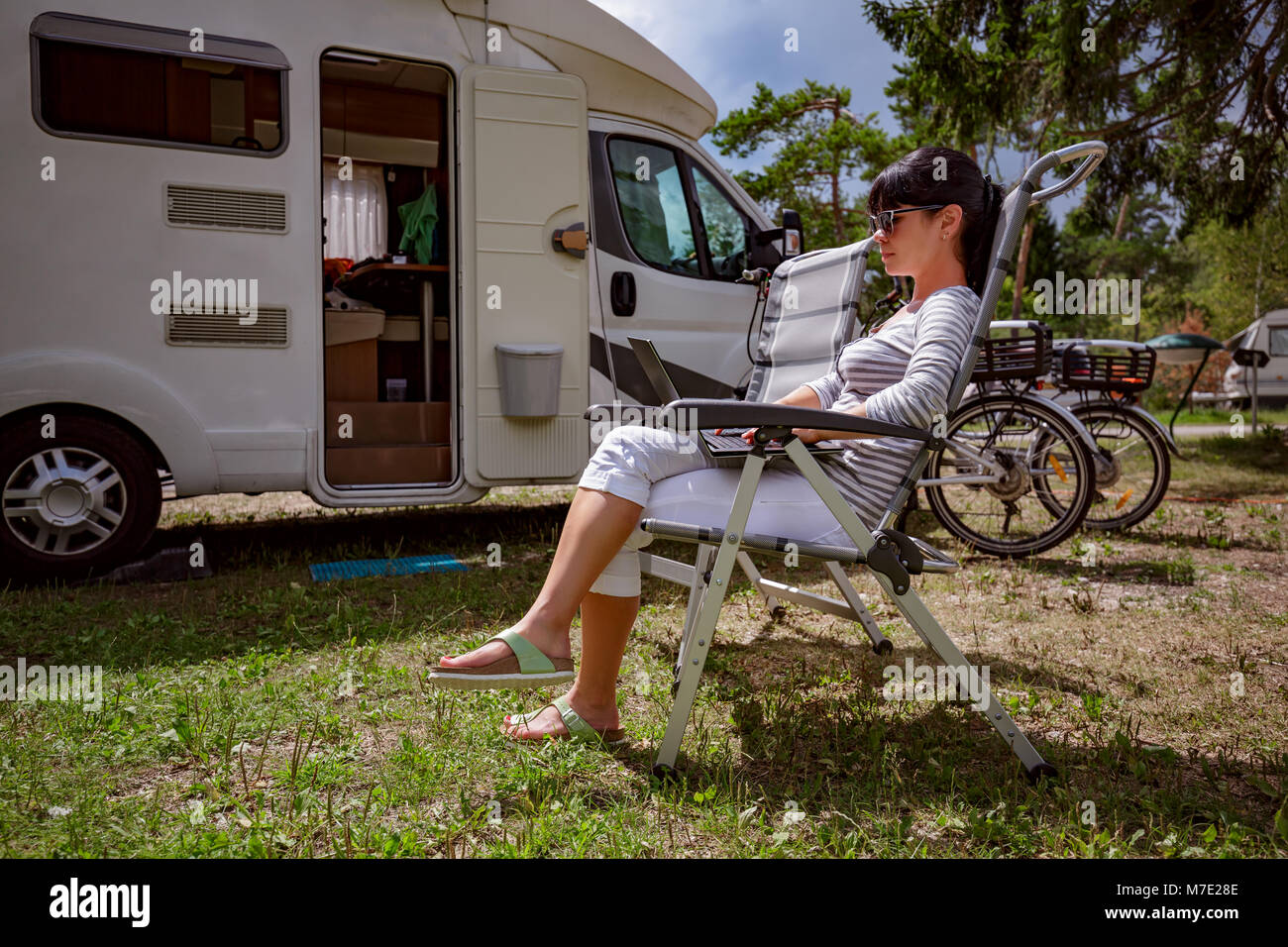 Frau auf dem Laptop in der Nähe des Camping. Caravan Auto Urlaub. Familie Urlaub Reisen, Urlaub im Reisemobil RV. Wi-fi Verbindung Informatio Stockfoto Frau auf dem Laptop in der Nähe des Camping. Caravan Auto Urlaub. Familie Urlaub Reisen, Urlaub im Reisemobil RV. Wi-fi Verbindung Informatio Stockfoto