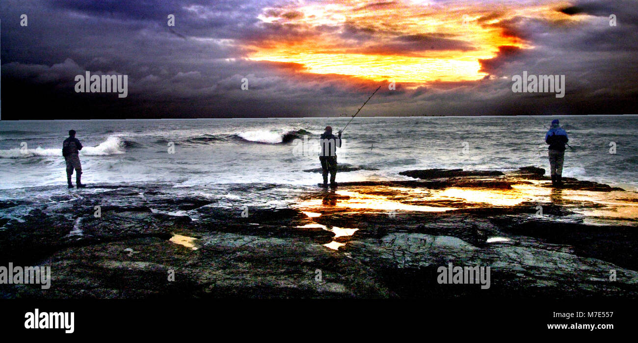 Drei Männer Fischen von den Felsen bei Sonnenuntergang in Newprt RI USA Foto bill Belknap Stockfoto