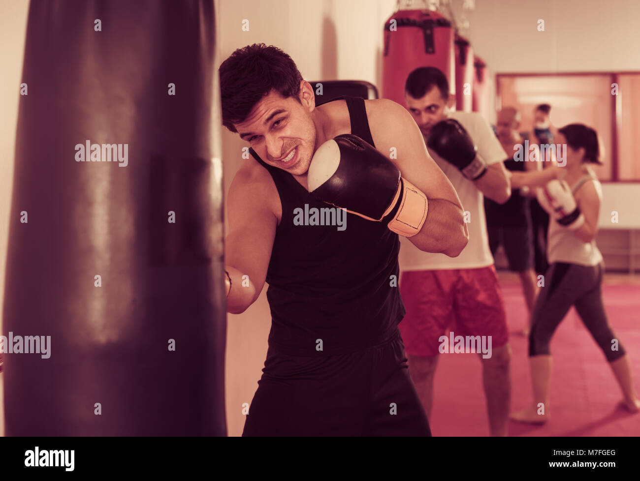 Anstrengenden Sportsman in der Halle üben Boxing Boxhandschuhe Stanzen mit Boxsack während des Trainings Stockfoto