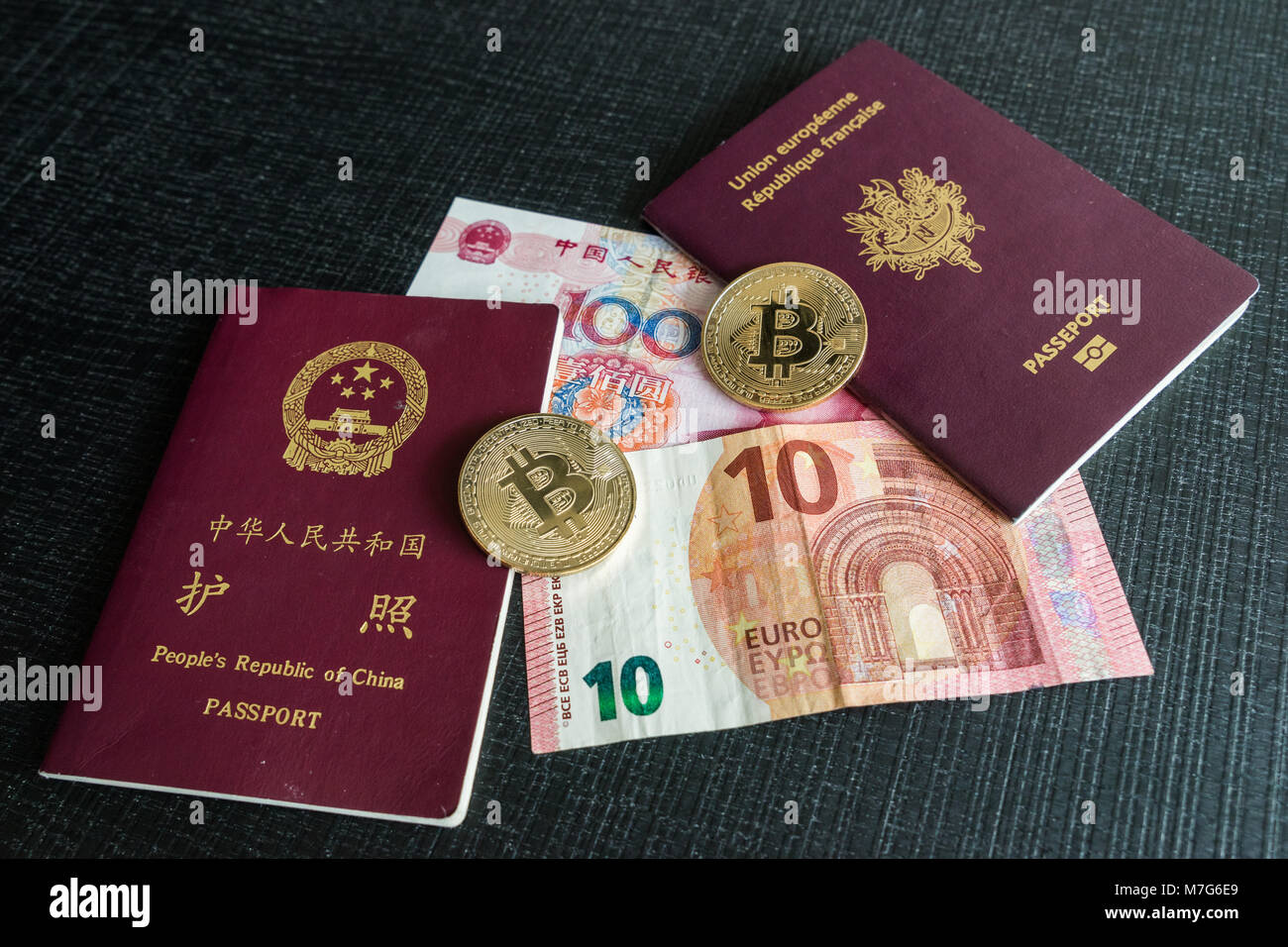 Chinesische und französische Reisepässe mit Euro und Yuan Banknoten und Bitcoins Stockfoto