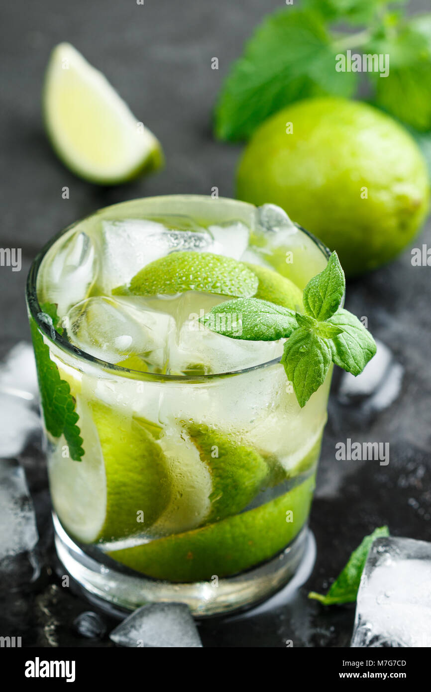 Kalt Erfrischende Sommer trinken mit Limette, Minze und Eiswürfel in einem Glas auf einem dunklen Stein Hintergrund. Mojito. Limonade. Detox. Mineralwasser. Selektive fo Stockfoto