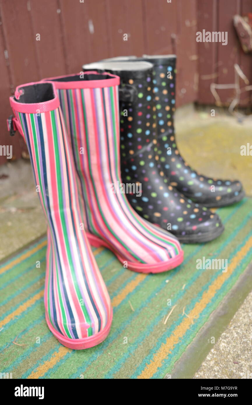 Zwei Paare von farbigen Frauen Landwirt oder Gärtner Stiefel auf ein Schlamm mat durch die Hintertür. Stockfoto