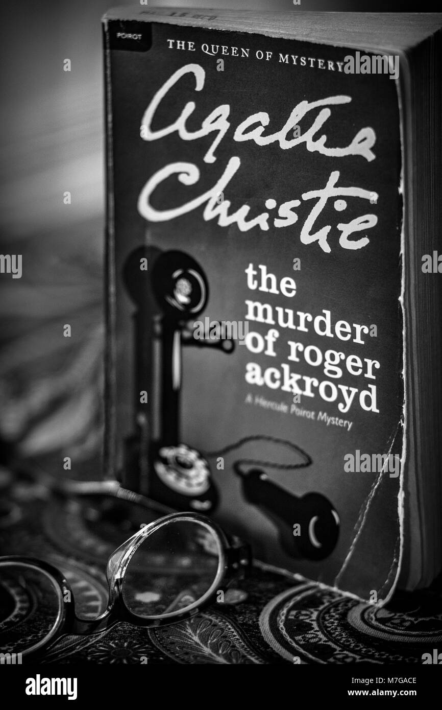 Ein Taschenbuch Roman Edition von Agatha Christie der Mord an Roger Ackroyd sitzt auf einem paisley Tischdecke, hinter einigen Lesebrille Stockfoto