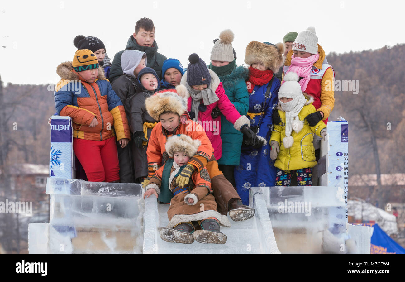 Hatgal, Mongolei, 4. März 2018: mongolische Kinder in traditioneller Kleidung auf einem zugefrorenen See Khuvsgul, unten kommen, eine Folie madeout von Eis Stockfoto