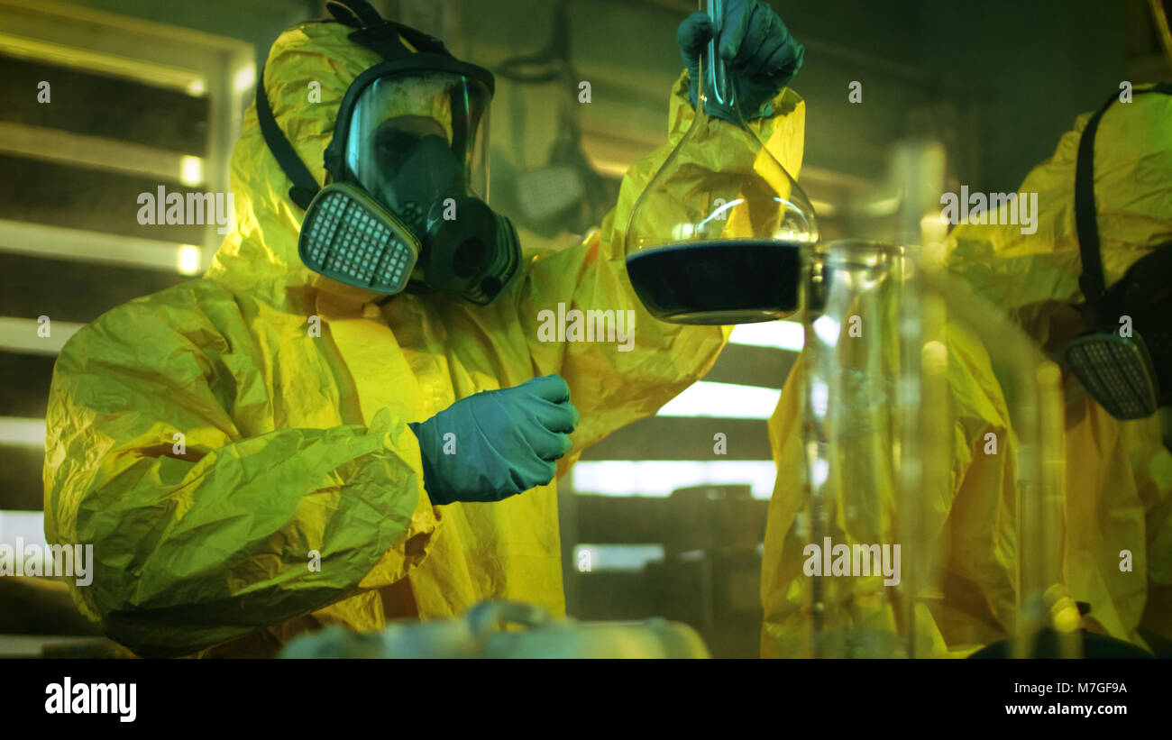 In der unterirdischen Droge Labor Team von heimlichen Chemiker synthetisiert illegale Drogen, Einer hält Becherglas mit Chemikalien und prüft es ist Konsistenz Stockfoto