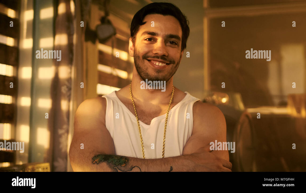 Stilvolle Hispanic Mann kreuzt die Arme und Smirks/Lächeln in die Kamera. Im Hintergrund verlassenen Gebäude mit an Bord. Stockfoto