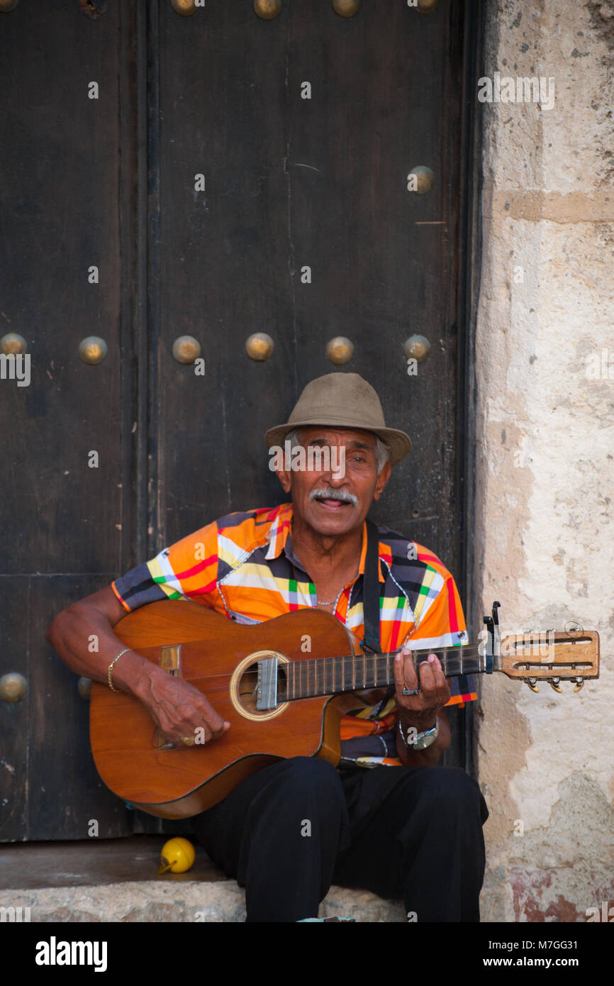 Ein bunt gekleideter Mann spielt Gitarre und singt in der Altstadt von Havanna, Kuba Stockfoto