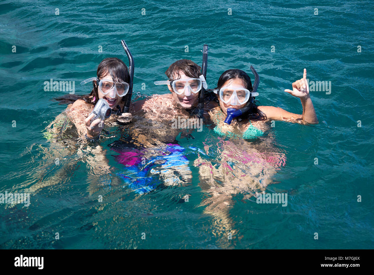 Drei junge Schnorchler (MR) frei Tauchen vor der Insel Lanai mit einer Unterwasser-Digitalkamera, Lanai, Hawaii. Stockfoto