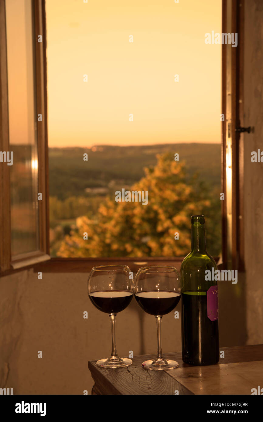 Weingläser und eine geöffnete Flasche Rotwein vor dem offenen Fenster, Südfrankreich. Stockfoto