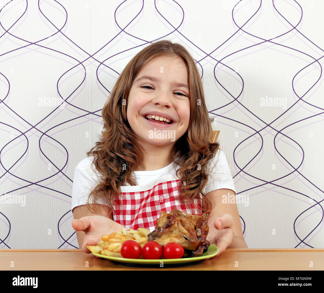 Glückliche kleine Mädchen mit gerösteten Chicken Wings auf Platte Stockfoto