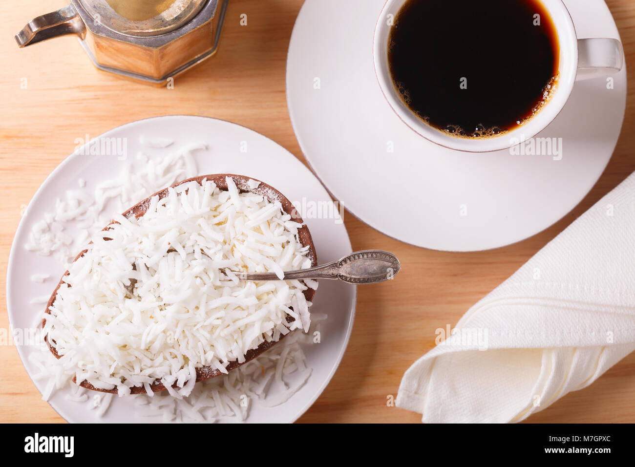 Ei Schokolade mit Füllung aus Kokos für Ostern und Tasse Kaffee auf Holz- Hintergrund. Selektiver Fokus Stockfoto