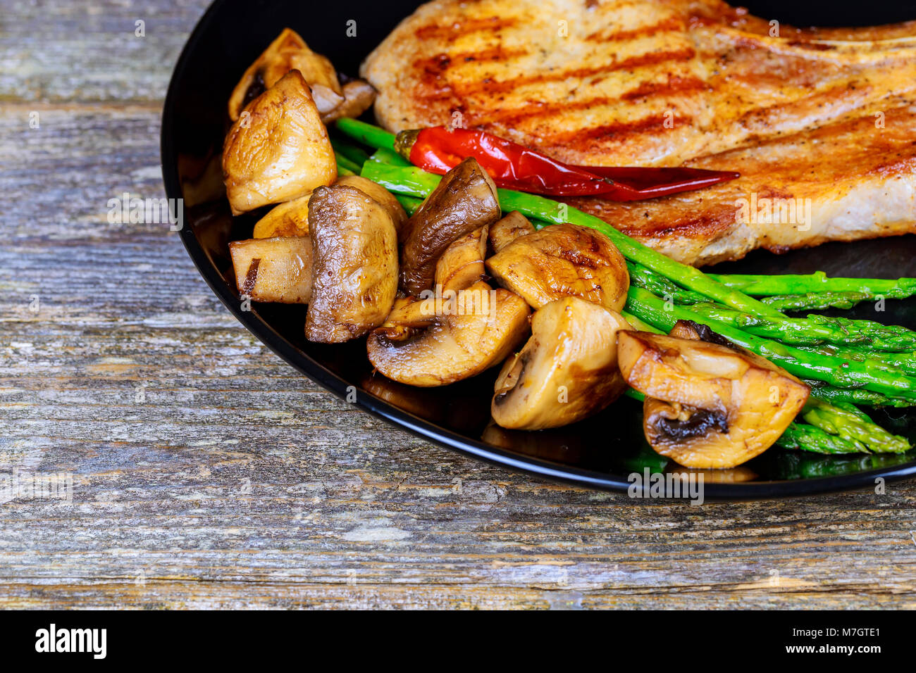 Schweinesteak mit Gemüse Spargel und Pilze Stockfoto