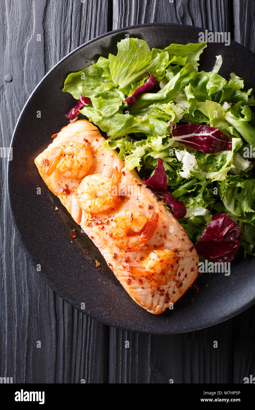 Leckeres essen: gebackene Lachs mit Garnelen in Honig Sauce und Salat auf einen Teller close-up auf einem Tisch. Vertikal oben Ansicht von oben Stockfoto