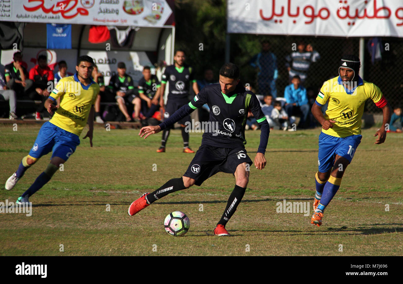 März 12, 2018 - Beit Lahia, Gazastreifen, Palästinensische Autonomiegebiete - Palästinensische Shabab Jabalia Football Club Spieler (in Gelb) und al-Hilal Football Club Spieler (in Schwarz) konkurrieren, während ein Fußballspiel im Stadion Beit Lahia im nördlichen Gazastreifen Am 11. März 2018 (Bild: © mahmoud Ajour/APA Bilder über ZUMA Draht) Stockfoto