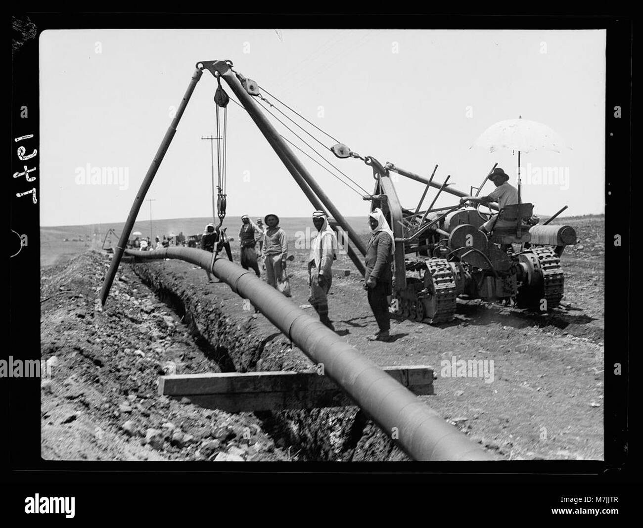 Ein Bild, auf dem Arbeiter der Irak Petroleum Company (I.P.C.) ein Rohr in einen Graben werfen und in der Region Esdraelon kurven. Das Foto dokumentiert die Entwicklung der Erdölinfrastruktur in der Region. Stockfoto