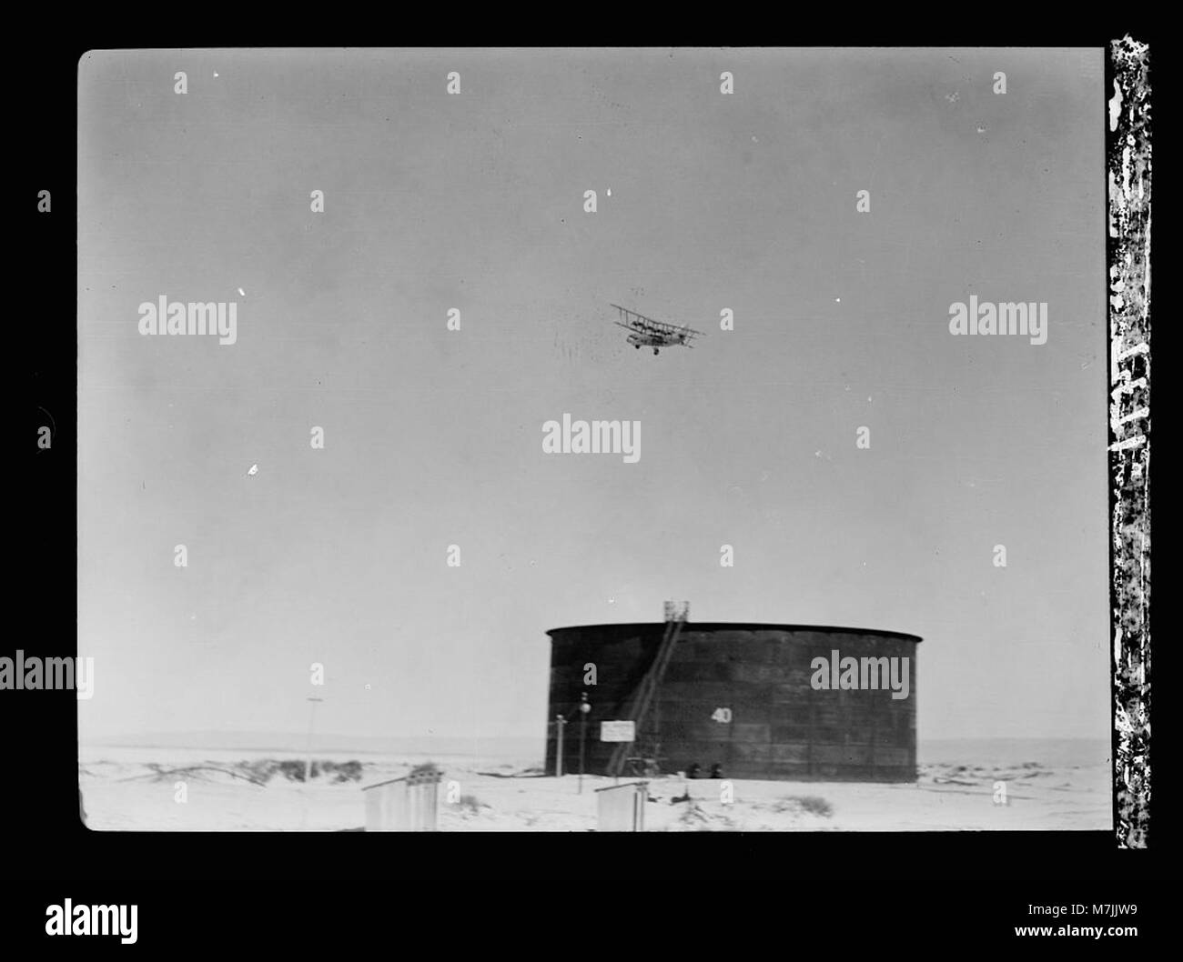 Dieses Bild zeigt einen Öltank der Irak Petroleum Company (I.P.C.) an der Endstation Haifa mit einem Flugzeug, das über dem Kopf fliegt. Das Foto spiegelt die Industrie- und Verkehrsinfrastruktur im Zusammenhang mit den Ölexporten des frühen 20. Jahrhunderts wider. Stockfoto