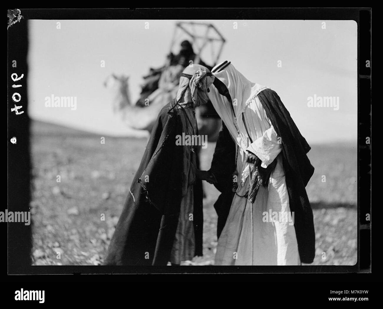 Ein Foto, das einen traditionellen Beduinengruß in Trans-Jordanien zeigt, bei dem zwei Männer die Stirn als Teil des Beduinengrußes berühren. Dieses Bild spiegelt die kulturellen Praktiken der Beduinen in der Region wider. Stockfoto