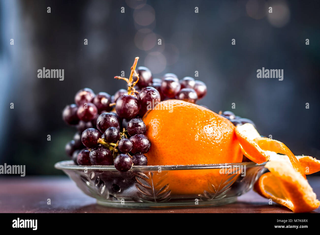 Traube, Vitis vinifera Obst und Orangen, Citrus aurantium in eine Glasschüssel auf Holz- Oberfläche. Stockfoto