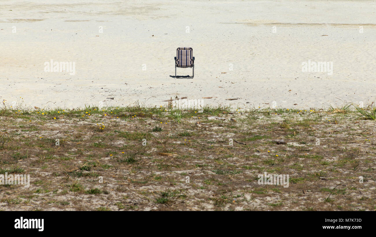 Ein einsamer Stuhl auf weißen Sand am Ufer des Sees Kia Iwi Stockfoto
