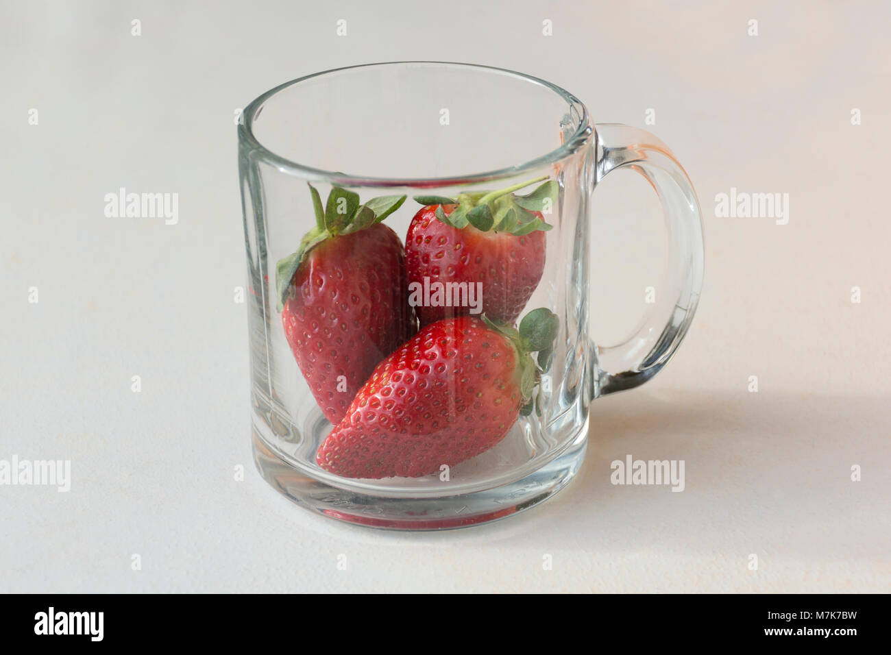 Drei schöne Rot, reif und lecker Erdbeeren in einem Glas Kaffee Tasse Stockfoto