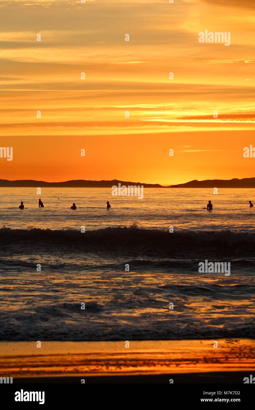 Orange Sonnenuntergang mit Silhouetten von Surfers Stockfoto